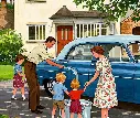A man and a woman teach their children how to wash their 1950s car on the driveway of an English hou... (1).webp
